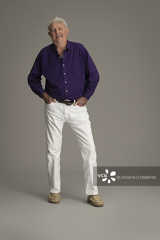 快乐的年长男人，身穿紫色衬衫和白色牛仔裤图片素材