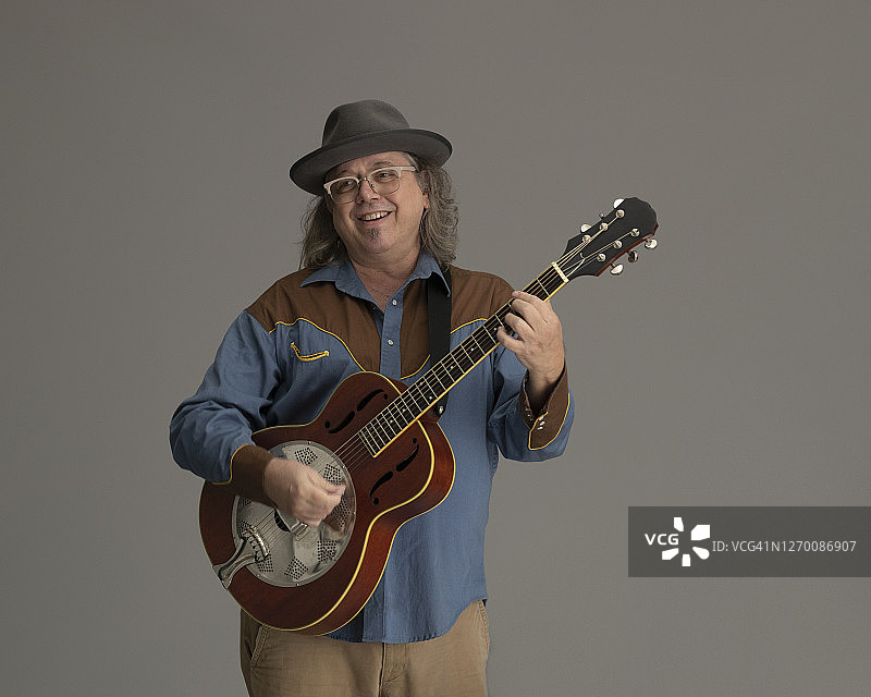 吉他手弹奏共鸣吉他，视线离开镜头图片素材