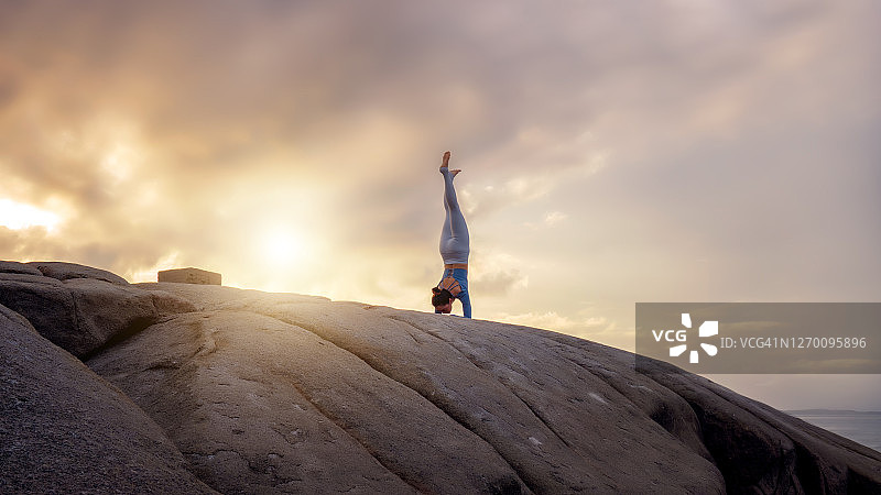亚洲女性在海边悬崖上做日出瑜伽图片素材