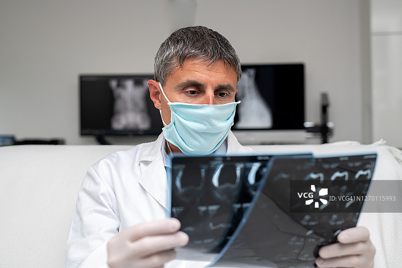医院：新冠肺炎，戴外科口罩的医生检查X光片的肖像图片素材