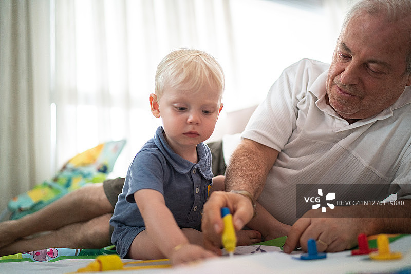 孙子在客厅地板上和爷爷玩耍图片素材