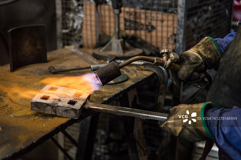 蓝领工人在车间使用火焰喷灯图片素材