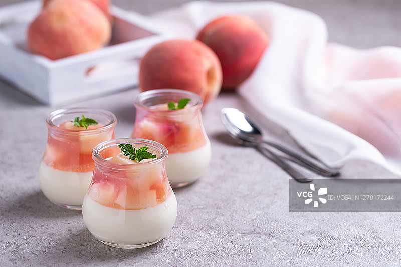灰色水泥背景上的自制意式奶冻配桃片和桃子果冻图片素材