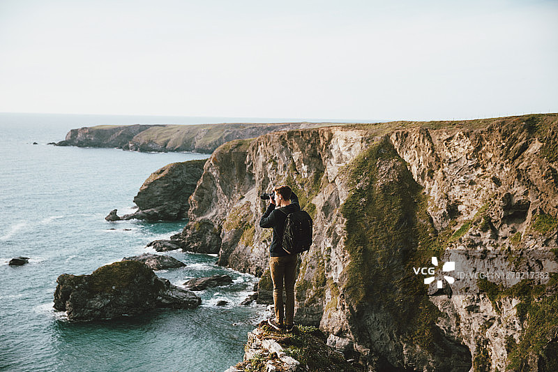 在风景优美海边悬崖上的男性摄影师图片素材