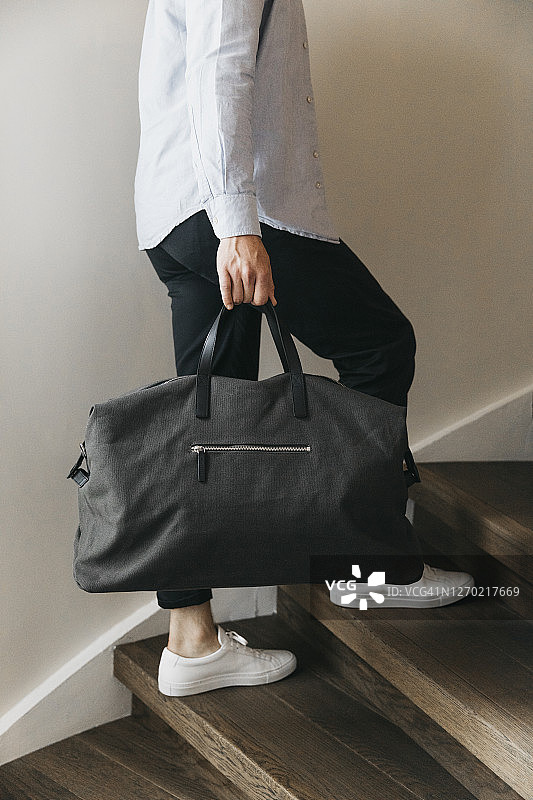 携带行李袋爬木楼梯的男人图片素材