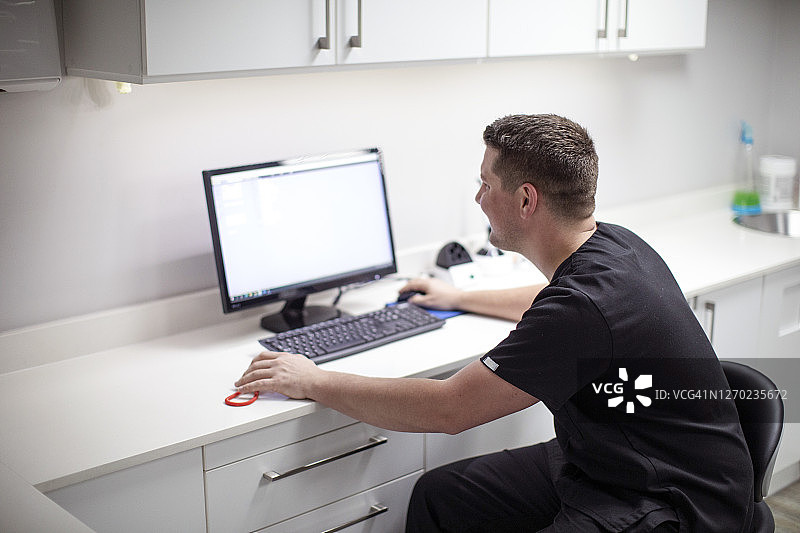 牙医在他的牙科工作室里用电脑工作图片素材