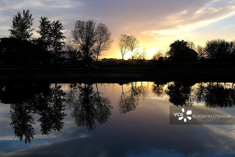 日落时分湖面倒映树木的剪影图片素材