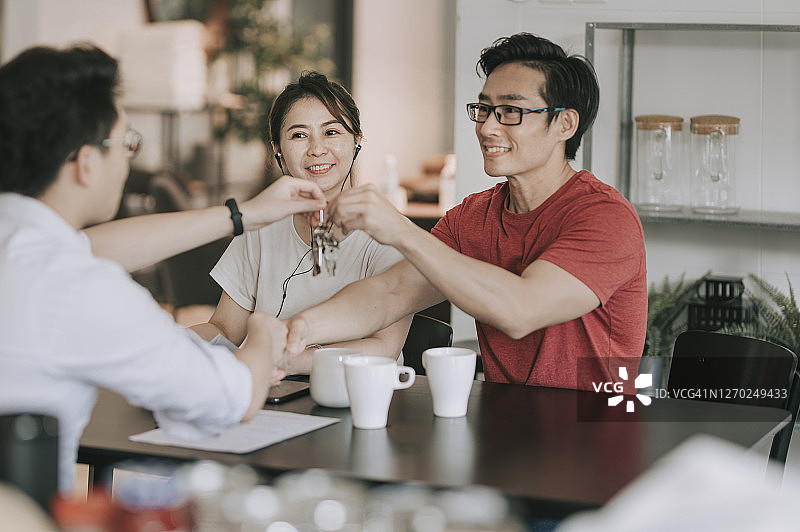 中国房地产经纪人在厨房与客户握手并移交房屋钥匙图片素材