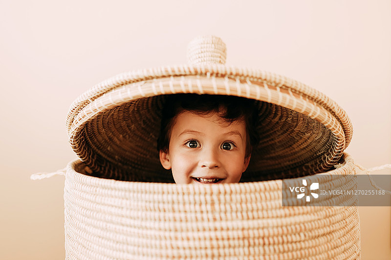 在家中柳条筐里嬉戏的快乐青少年男孩图片素材