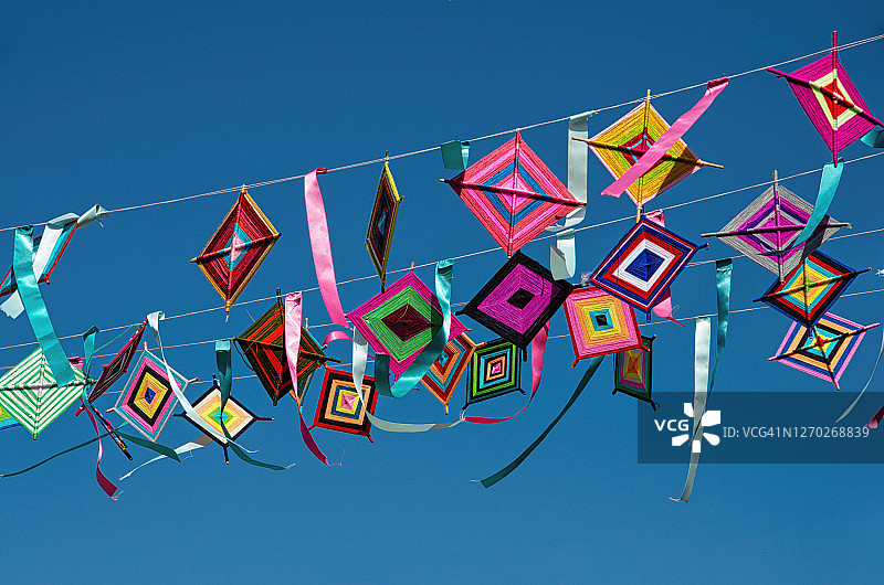 悬挂在街道上空的“神之眼”和彩带，背景是明亮的蓝天图片素材