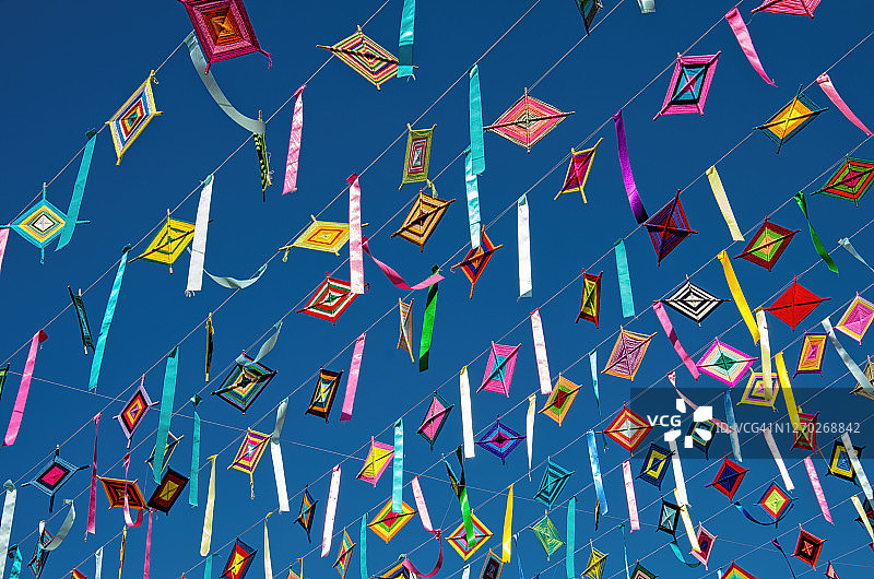 悬挂在街道上空的“神之眼”和彩带，背景是明亮的蓝天图片素材