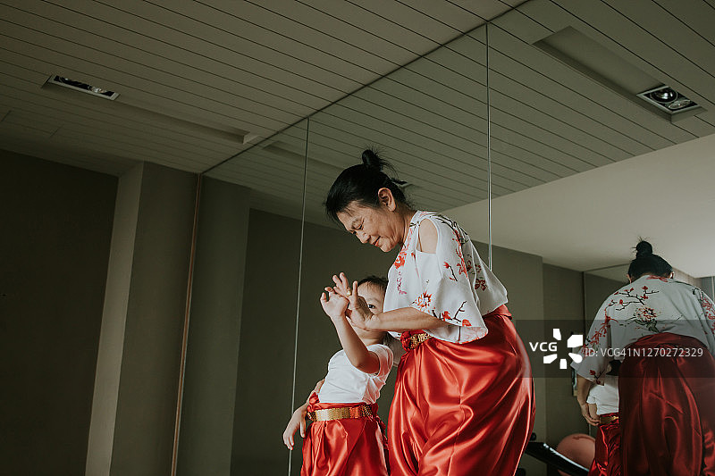 年长的女人教可爱的女孩跳泰国传统舞蹈图片素材