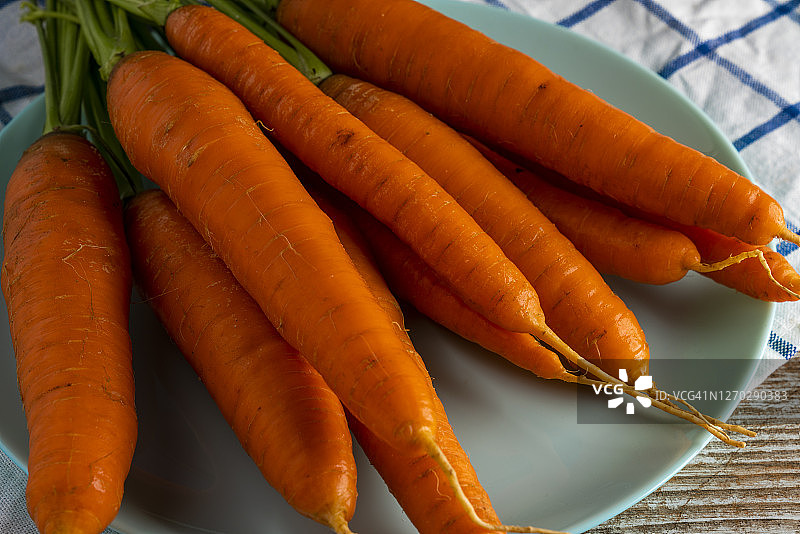 盘子里旧木桌上的成捆胡萝卜图片素材