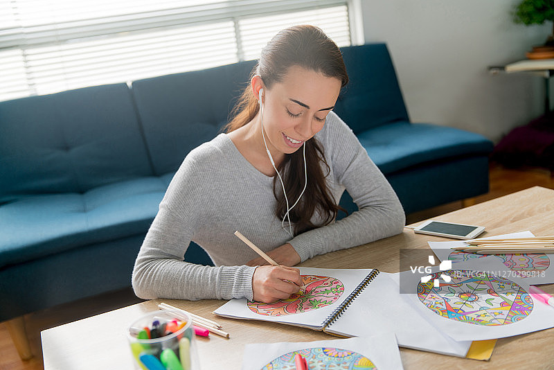 女人在家中一边听音乐一边涂色曼陀罗图片素材