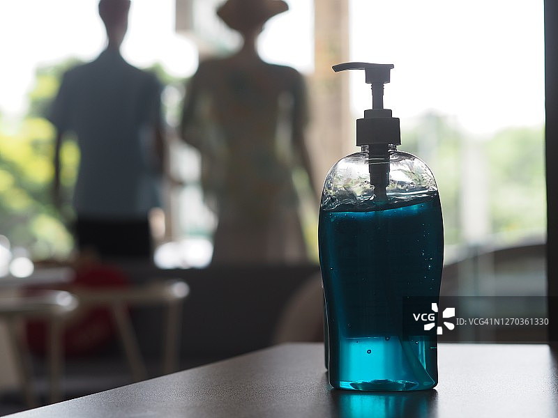 洗手液，透明塑料瓶中含酒精混合物，用于按压清洗，防止细菌感染，保护木桌上的传染病冠状病毒 covid-19图片素材
