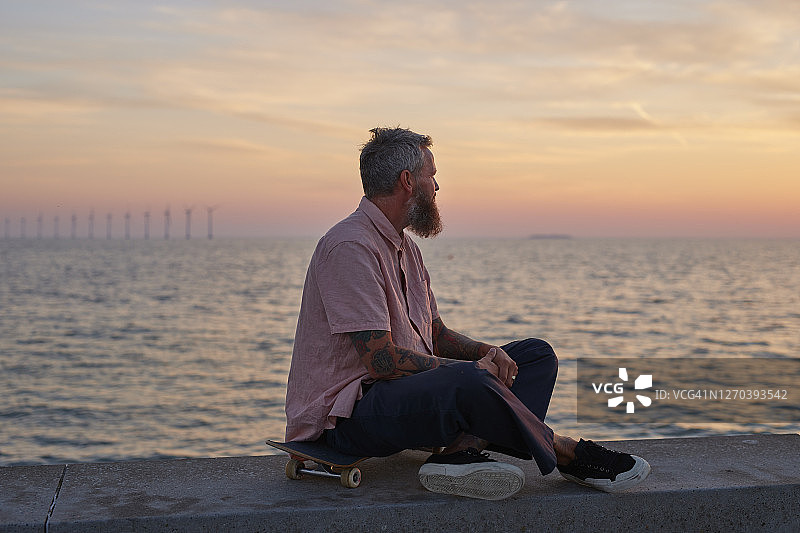 滑着滑板在日落时分欣赏天空的时尚人士图片素材