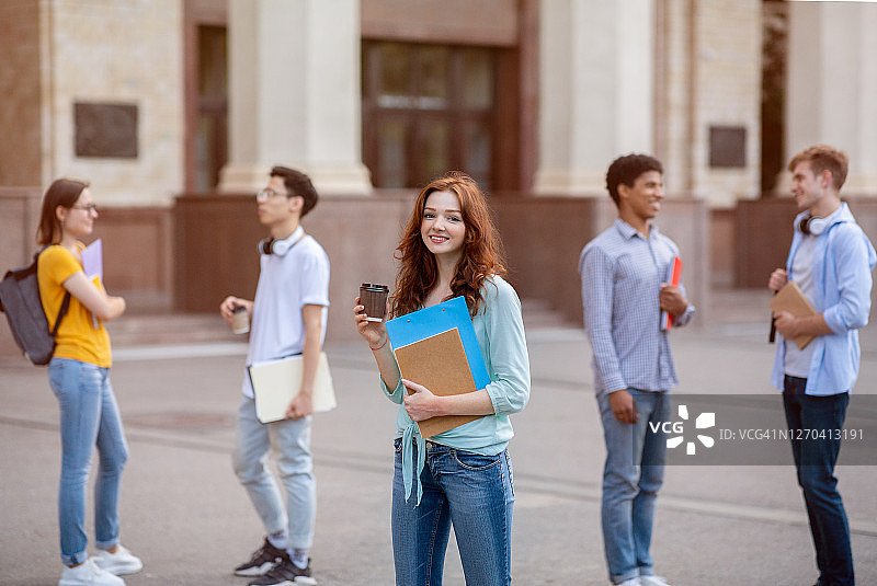 快乐的女大学生在大学外休息时喝咖啡图片素材