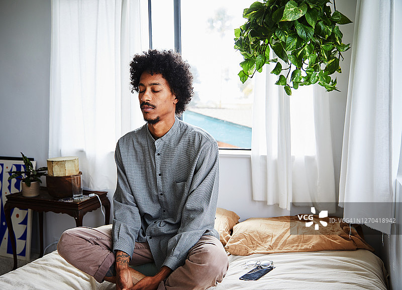 年轻男人在卧室里闭目冥想图片素材