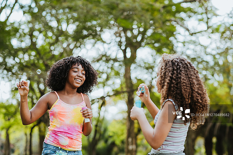 两个女孩吹肥皂泡泡玩得很开心图片素材