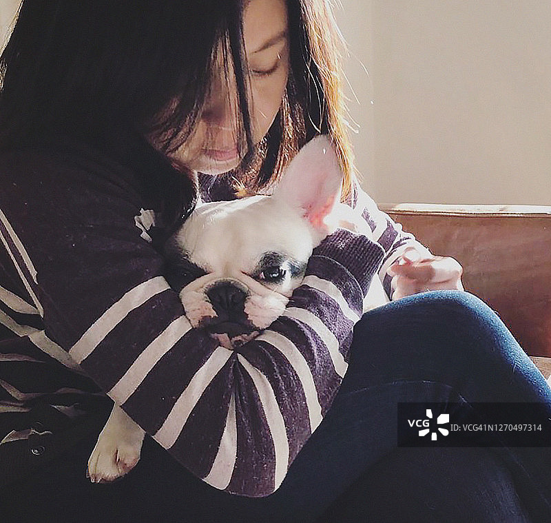 拥抱她的狗的亚洲中国女人的肖像图片素材