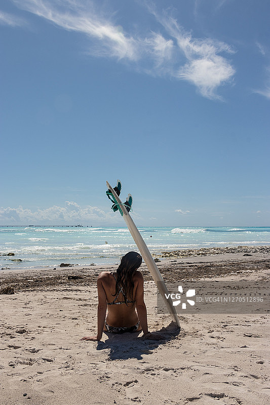 坐在沙滩冲浪板下的女人图片素材