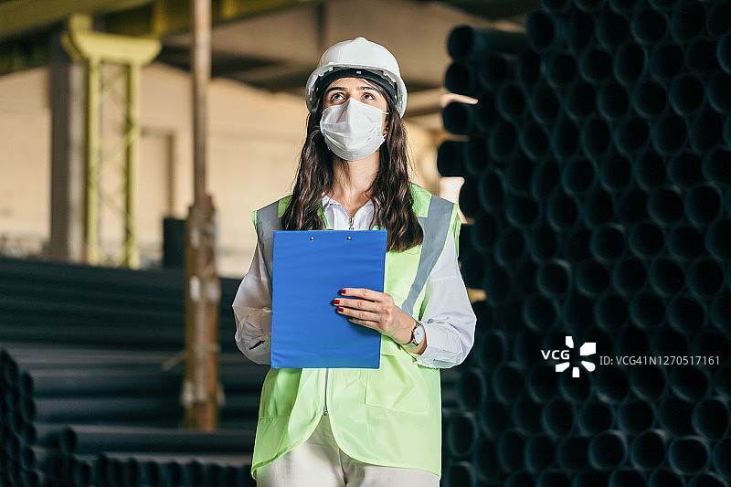 女工程师戴防护面罩和防护服检查管材质量图片素材