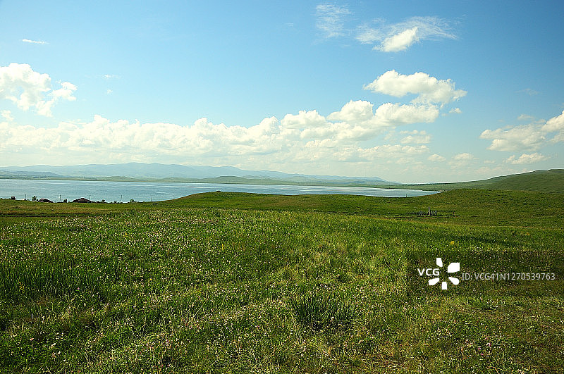 大湖岸边山坡上的长草原和几栋小房子图片素材