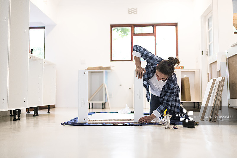 女人用力组装新的厨房橱柜图片素材