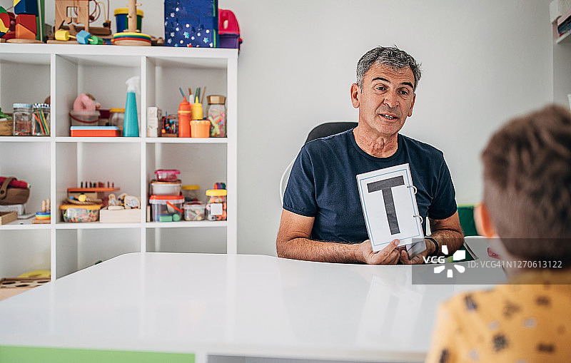 言语治疗师教男孩说字母T图片素材