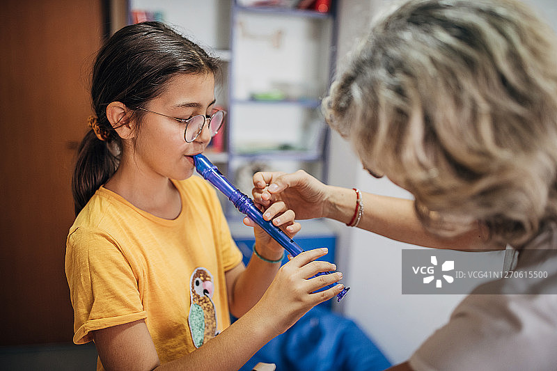 音乐课上，女孩和女老师一起吹长笛图片素材