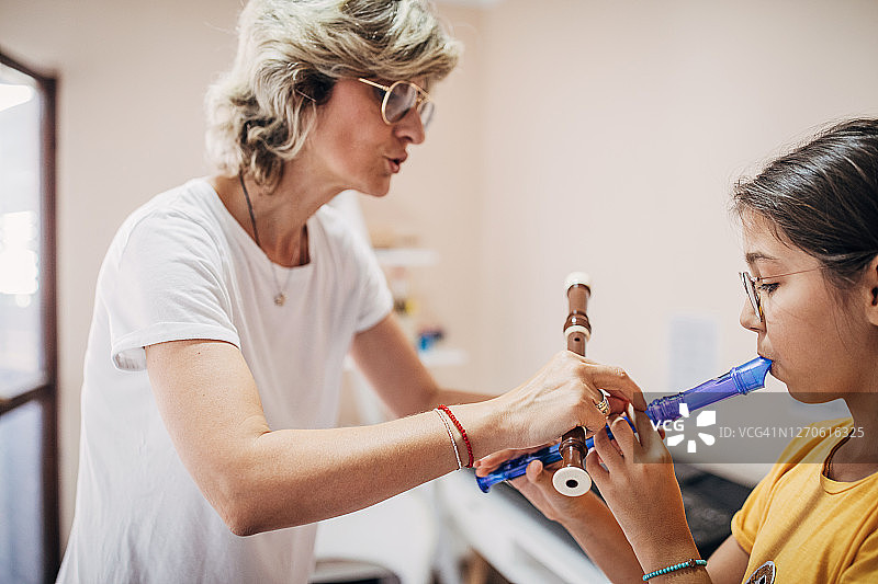 音乐课上，女孩和女老师一起吹长笛图片素材