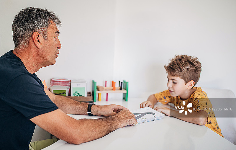 学龄前男童在语言治疗师的指导下学习字母图片素材