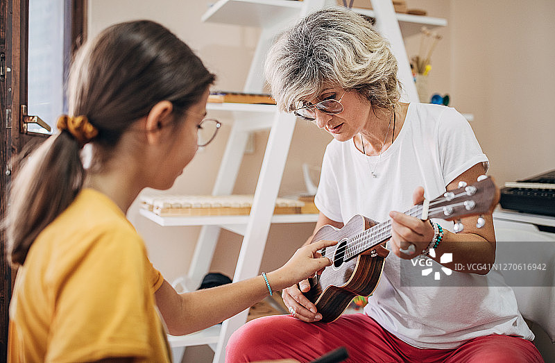 音乐课上和女老师一起学习弹吉他的女孩图片素材