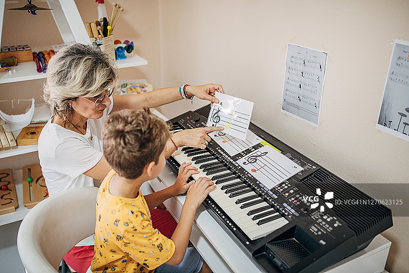 学龄前男孩和音乐老师学习弹奏合成器图片素材