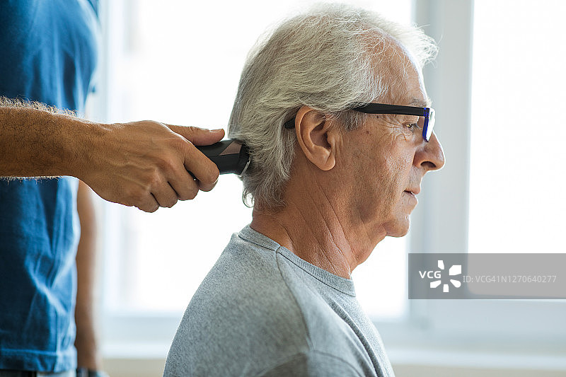 父亲在家用电动剃须刀为儿子理发图片素材