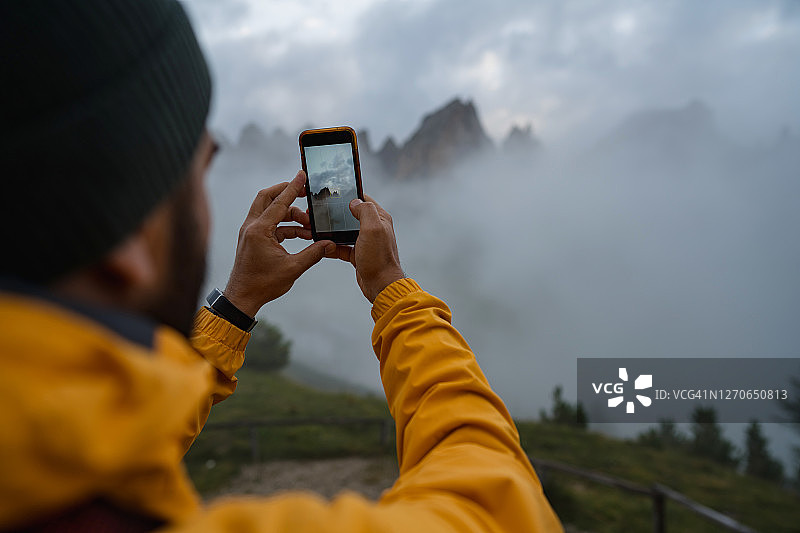 男子用手机拍摄雾日多洛米蒂山图片素材
