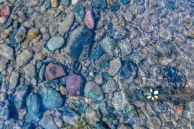 水下闪耀的石头鹅卵石。清澈的绿松石色水流流过鹅卵石图片素材