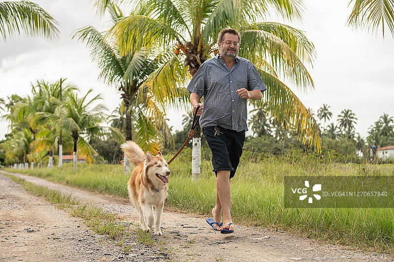 在海滩上与狗奔跑的男人图片素材