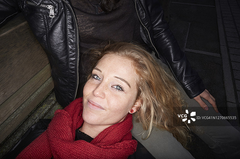 笑容满面的年轻女子躺在朋友的腿上图片素材