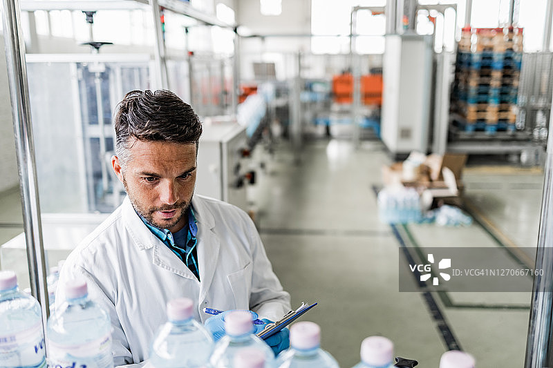 在瓶装工厂检查装运前水瓶的男人图片素材