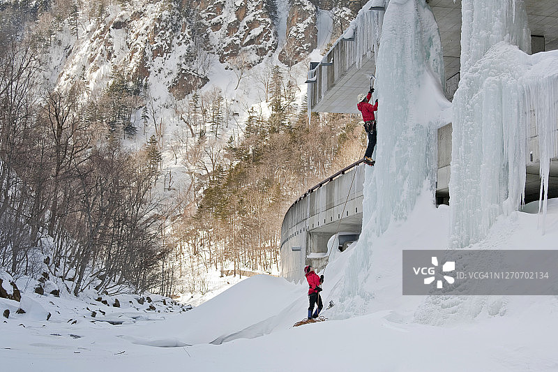 男人在北海道大雪山国家公园层云峡的公路上攀登冰柱图片素材