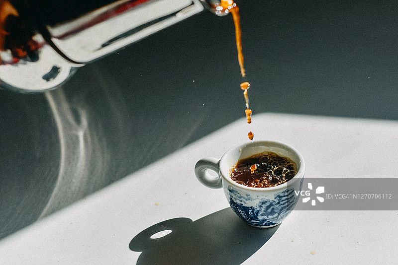 摩卡壶向浓缩咖啡杯中倒咖啡的特写图片素材