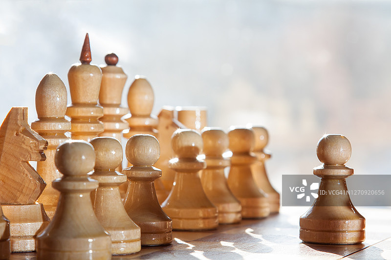 白色木制棋子与前方士兵的象棋棋盘，背景模糊图片素材
