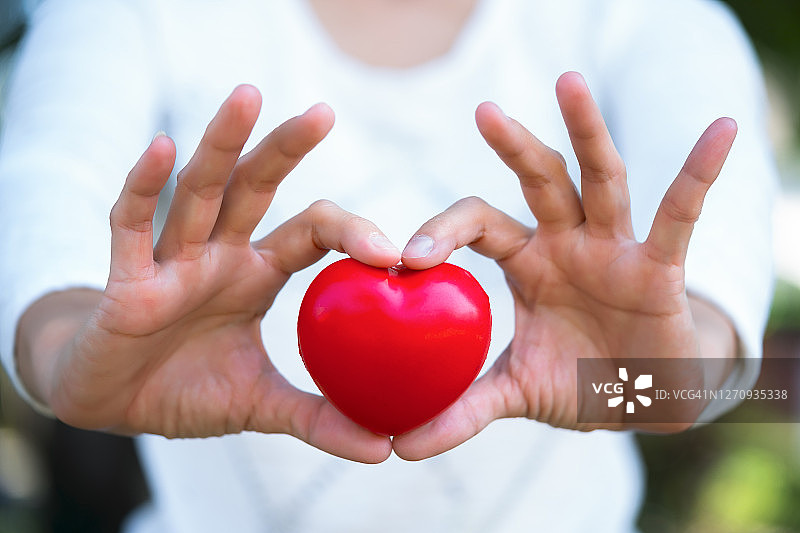 手持红色爱心的女性身体中部特写图片素材