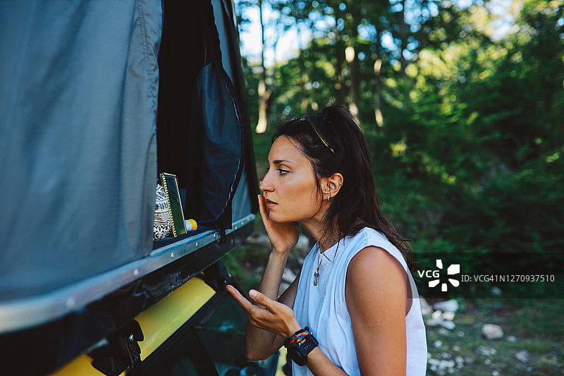 年轻女子在露营旅行的早晨使用护肤品图片素材