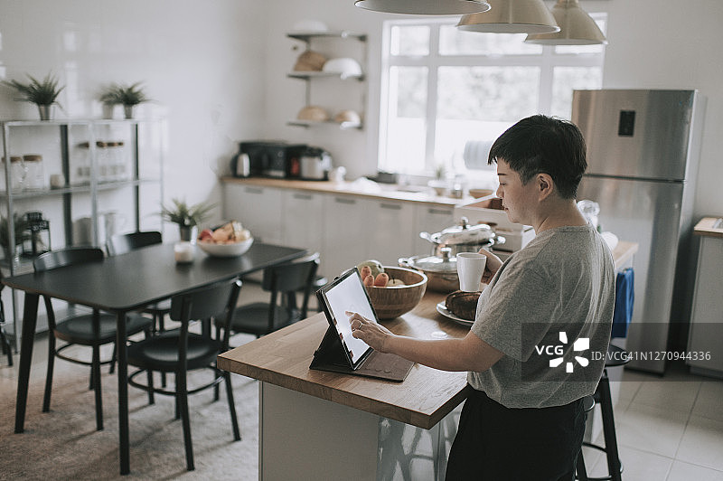 在厨房使用平板电脑的亚洲中年妇女图片素材