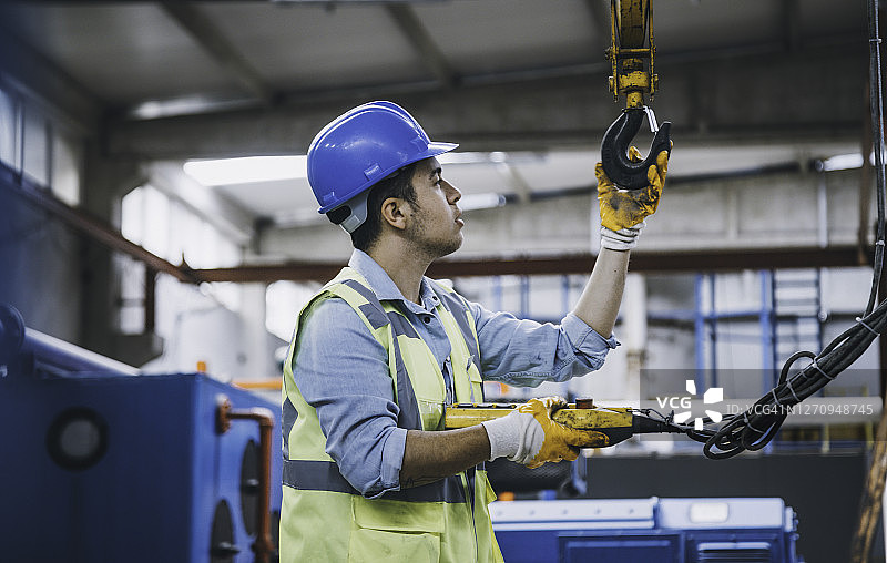 手持遥控器操作起重机的年轻商人图片素材