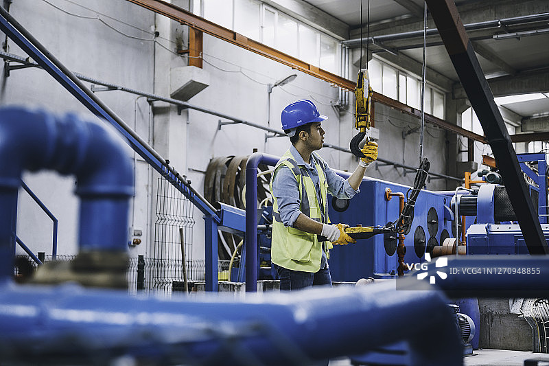 手持遥控器操作起重机的年轻商人图片素材