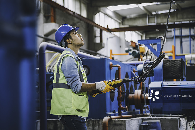 手持遥控器操作起重机的年轻商人图片素材