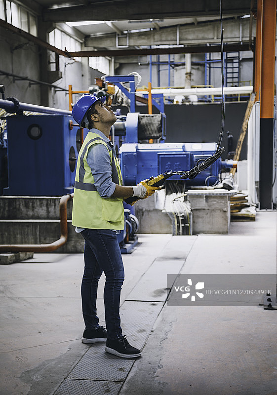 手持遥控器操作起重机的年轻商人图片素材